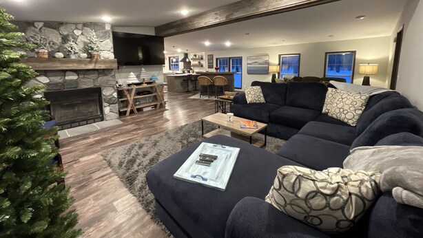 A modern living room with a fireplace, a large sofa, and a dining area. - Superior Adventures — Luxury 80-Acre Executive Retreat (Shingleton)