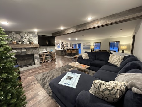 A modern living room with a fireplace, a large sofa, and a dining area.