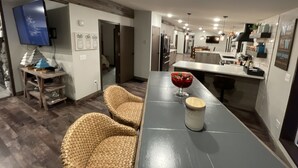A modern kitchen with a dining area, wooden flooring, and a flat-screen TV mounted on the wall. - Superior Adventures — Luxury 80-Acre Executive Retreat (Shingleton)