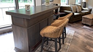A modern kitchen with a central island, bar stools, a sofa, and a coffee table. - Superior Adventures — Luxury 80-Acre Executive Retreat (Shingleton)