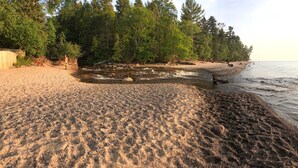 A pebbled beach with a river, trees, and a wooden structure. - Superior Adventures — Luxury 80-Acre Executive Retreat (Shingleton)