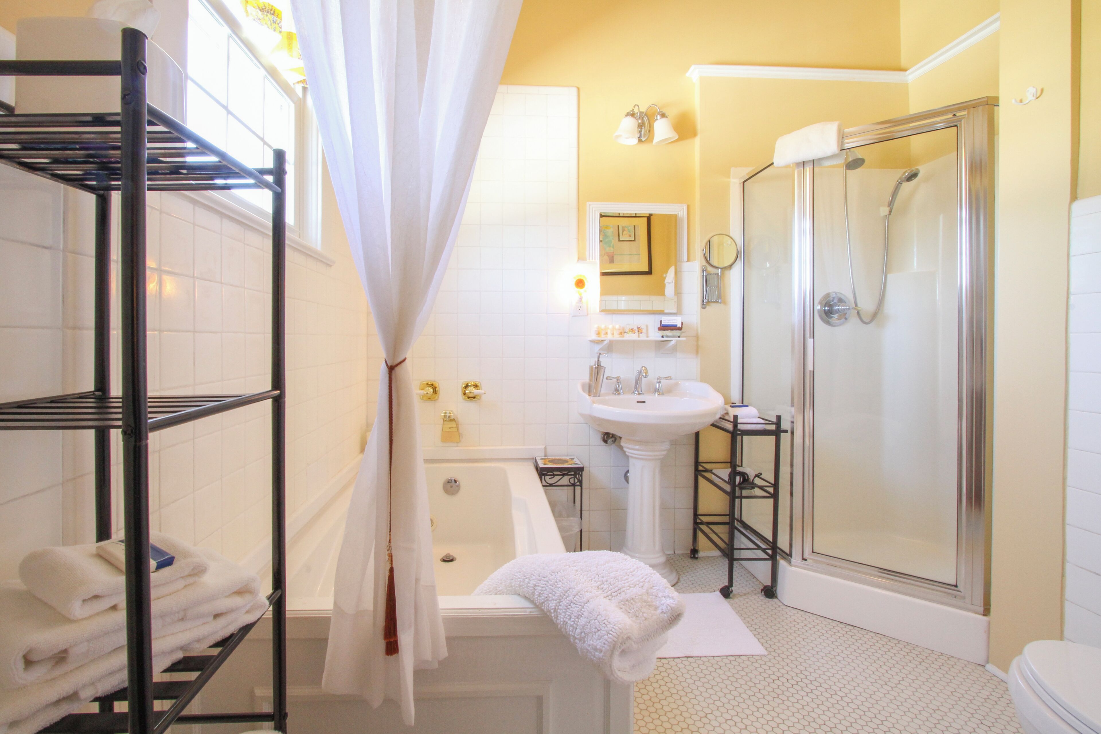 A bathroom with a bathtub, a shower, a sink, and a shelf with towels.