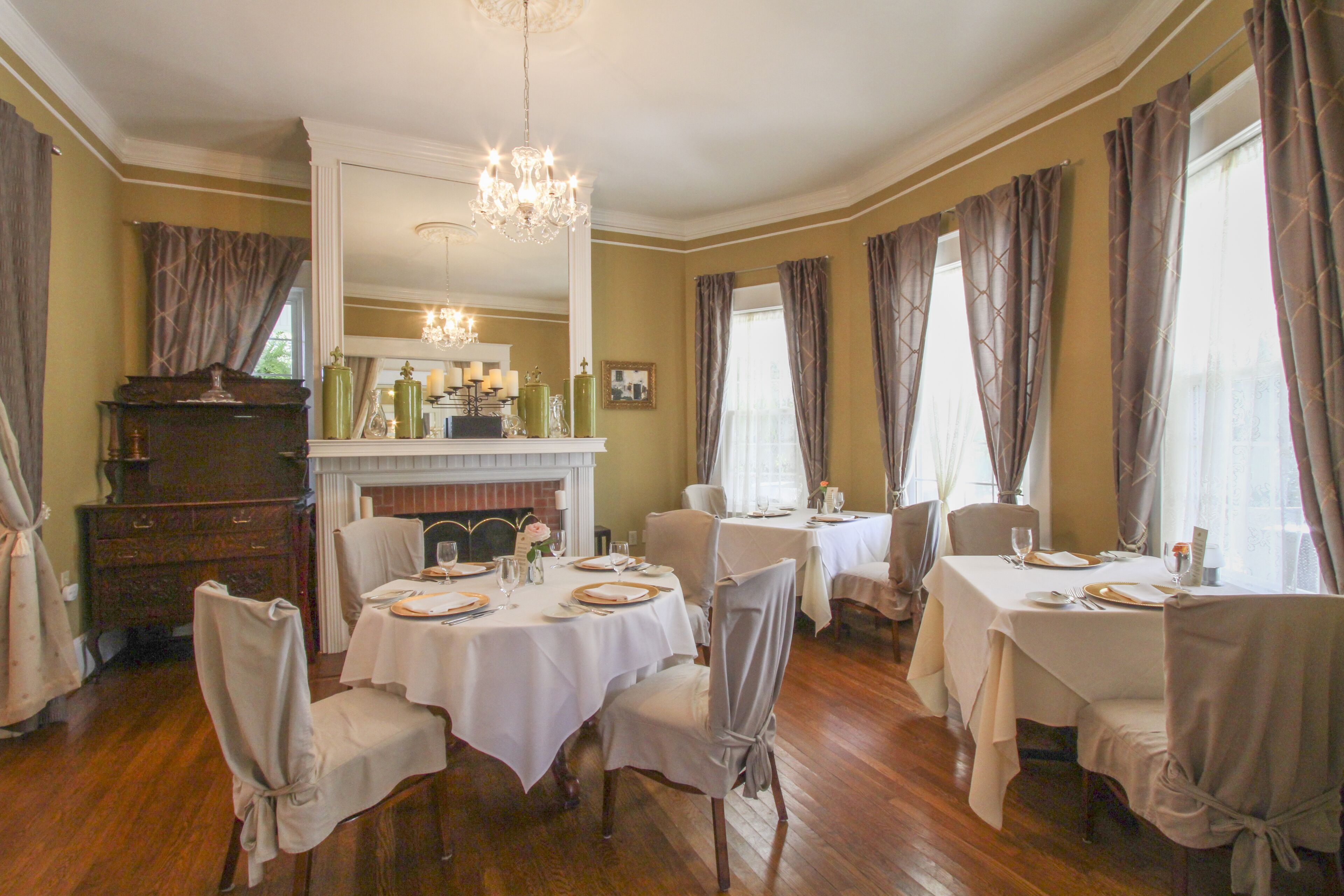 A dining room with multiple tables set for a meal, a fireplace, and a chandelier.