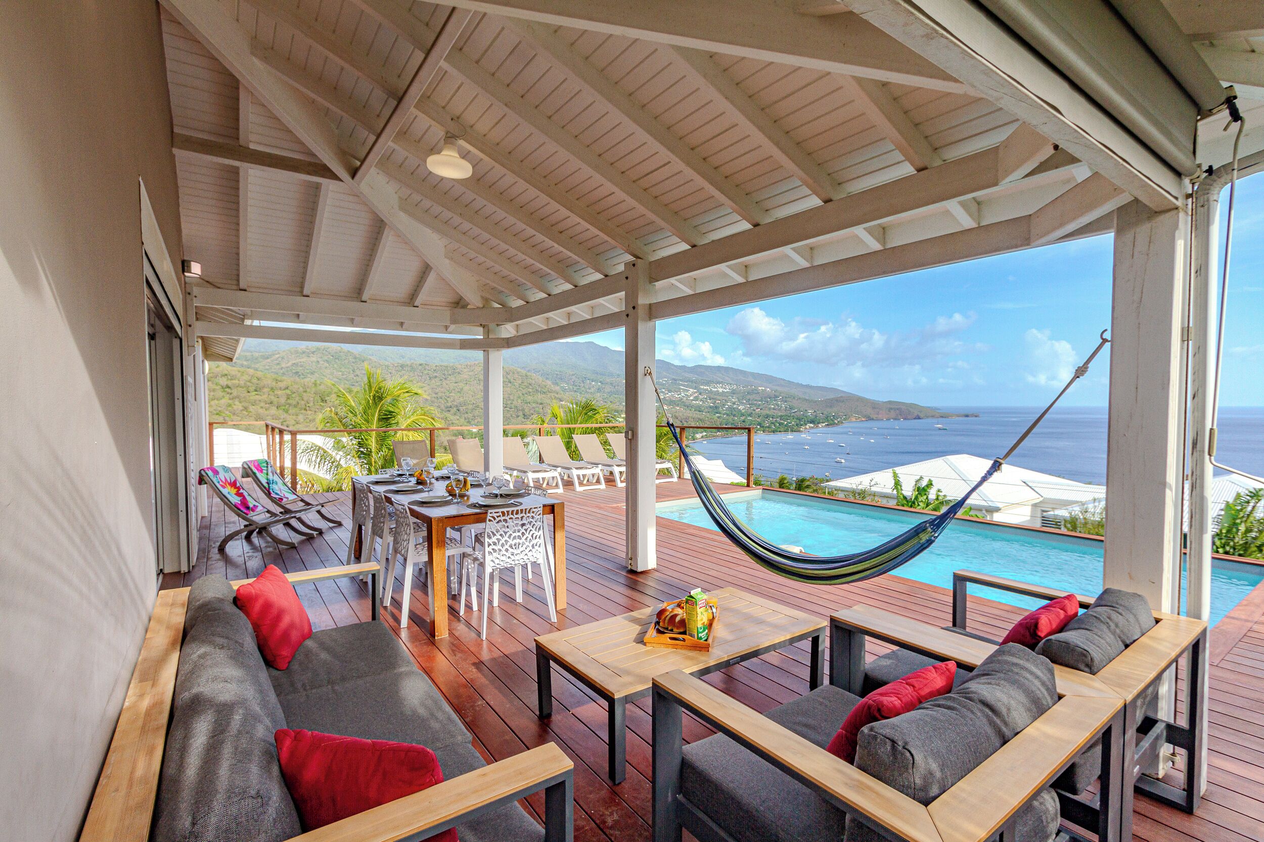 A covered outdoor area with a pool, seating, and a hammock.