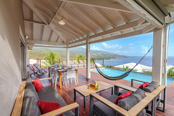 A covered outdoor area with a pool, seating, and a hammock.