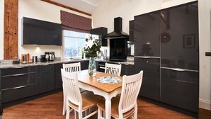Een moderne keuken met donkere kastjes, een houten eettafel en witte stoelen.