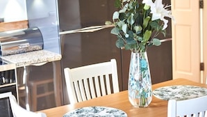 Een eettafel met een bloemenvaas en een tafelonderzetter met bloemen.