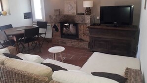 Un salon chaleureux avec une cheminée en pierre, un téléviseur et des fauteuils confortables.