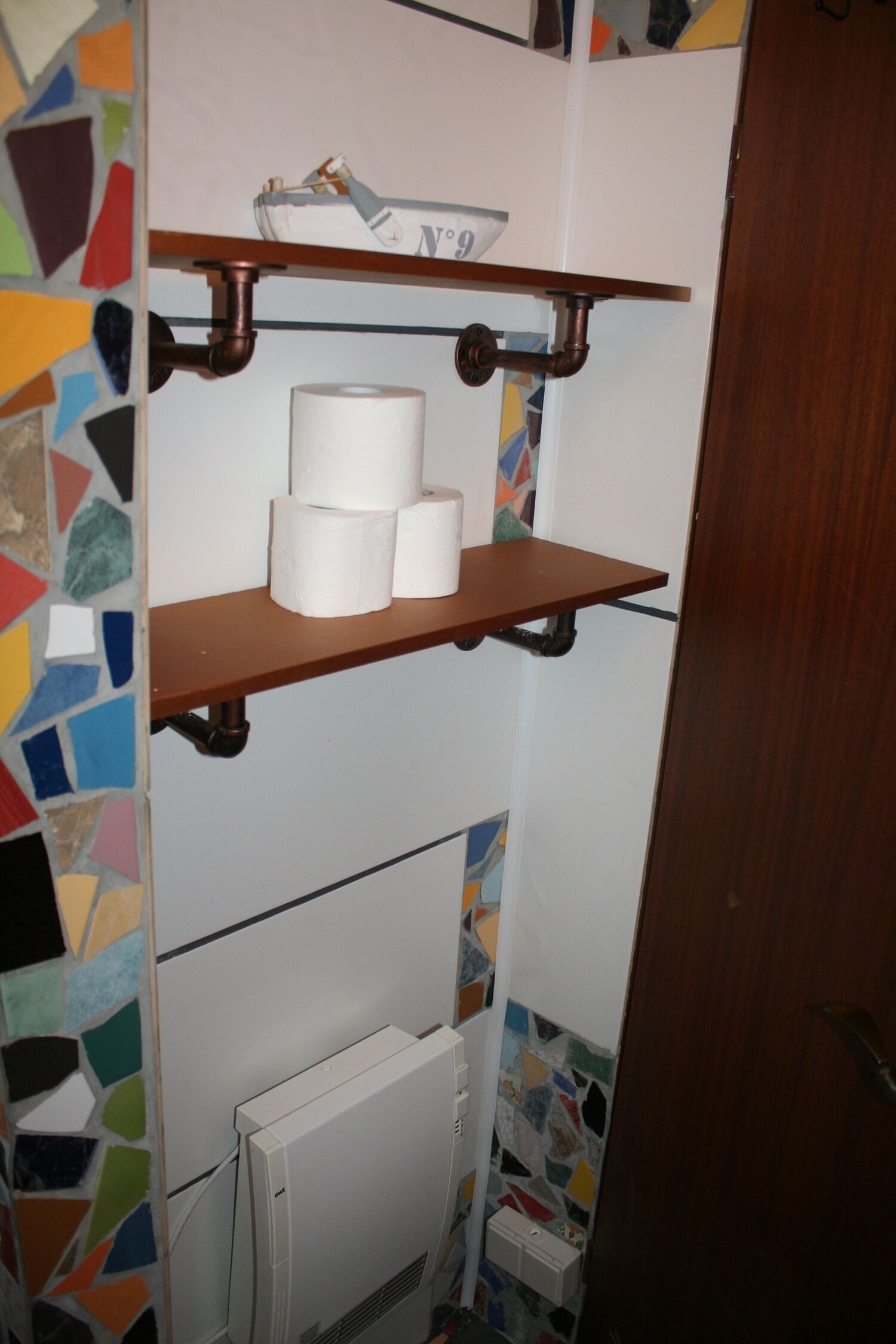 A bathroom with a toilet paper holder, a radiator, and a tiled wall.
