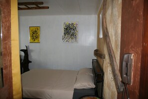 Een kamer met een bed, een telefoon en twee kunstwerken aan de muur.