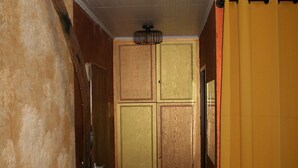 Un couloir étroit avec une porte en bois, une petite table sur laquelle se trouve une pizza et un rideau jaune.