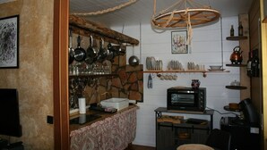 Une cuisine avec des casseroles suspendues, un four à micro-ondes et un plafond rustique.