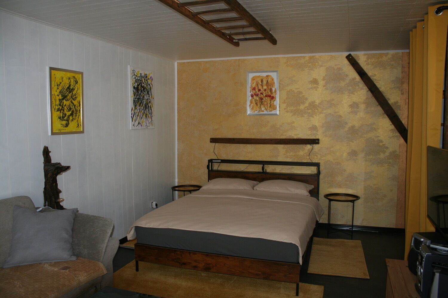 A bedroom with a bed, a wooden headboard, a nightstand, a lamp, and a chair.