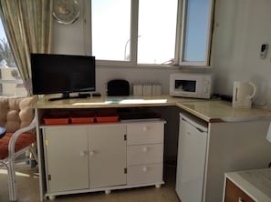 A compact kitchenette with a microwave, kettle, and a small cabinet with drawers.