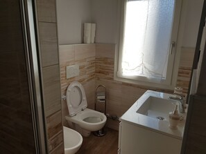 A modern bathroom with a toilet, bidet, and sink.