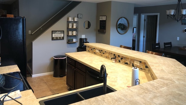 A modern kitchen with a central island, dark cabinetry, and a stone backsplash.