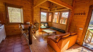 A cozy wooden cabin with a dining area, a sofa, and a small kitchen. - Casa 2 Urdieta, waterfall house (Angulo)