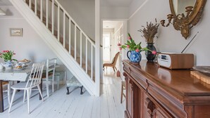 Eine Treppe führt zu einem Essbereich mit einem für zwei Personen gedeckten Tisch, einer Blumenvase und einem Vintage-Radio.