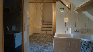 Un baño moderno con bañera, zona de ducha y suelo de baldosas.