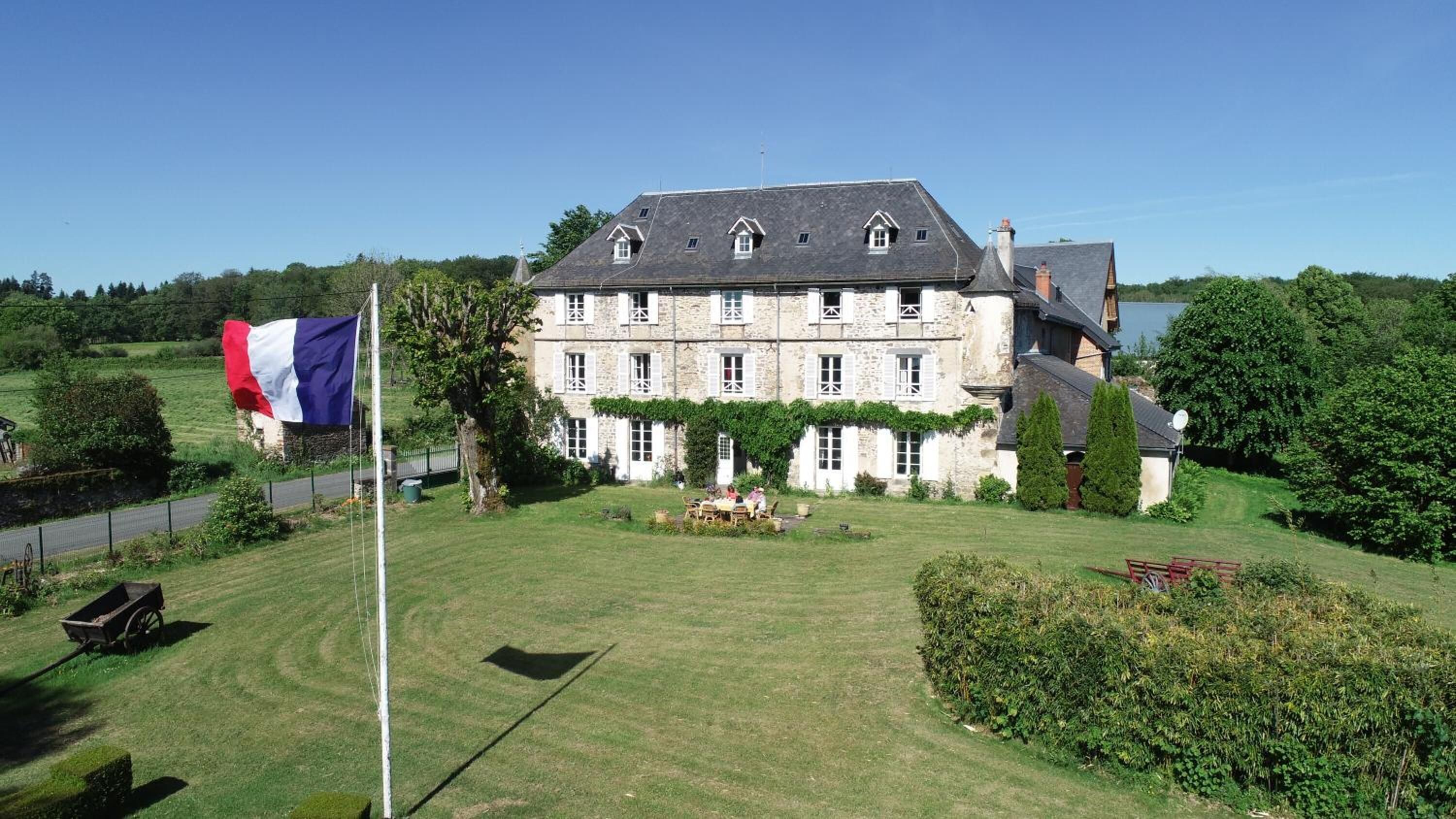 A large stone building with multiple windows and a flagpole with a flag.