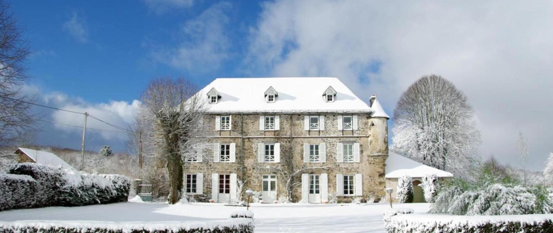 A large stone building with multiple windows and a snow-covered roof.
