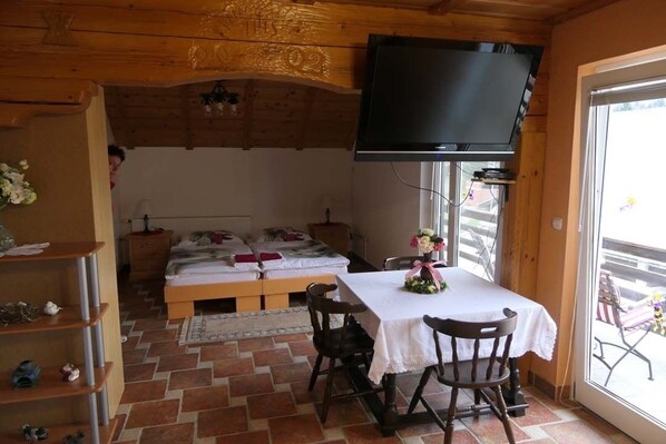 Ett mysigt rum med en säng, ett bord med stolar, en tv som är monterad på väggen och ett fönster med utsikt.