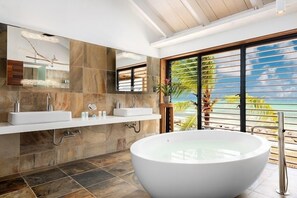 Ein modernes Badezimmer mit einer großzügigen, freistehenden Badewanne, einem Doppelwaschtisch und einem großen Spiegel.
