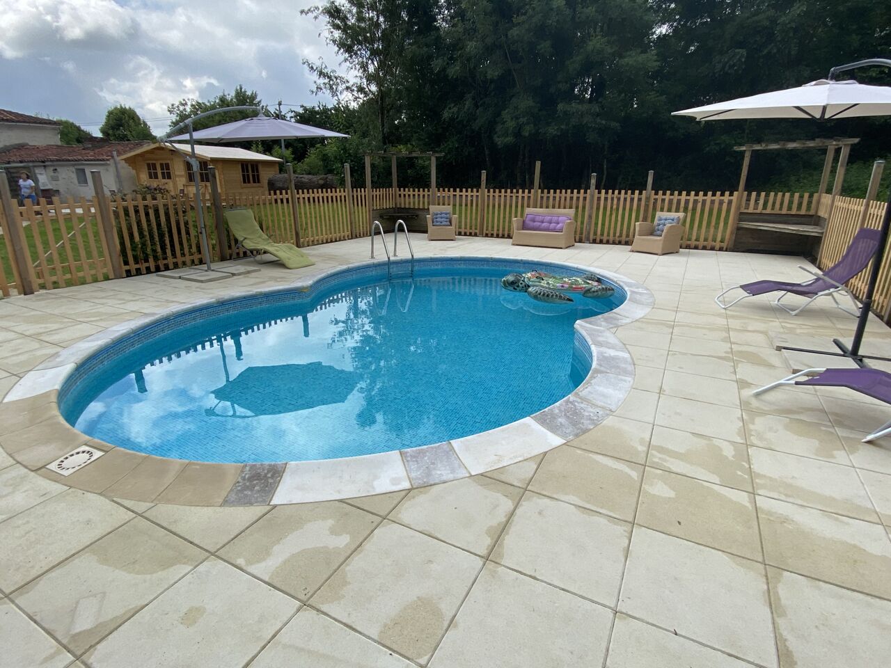 Ein Schwimmbecken mit Holzterrasse, Liegestühlen und Sonnenschirmen.