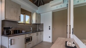 Una cocina moderna con horno empotrado, cafetera y mesa de comedor de madera con un centro decorativo de piedra.
