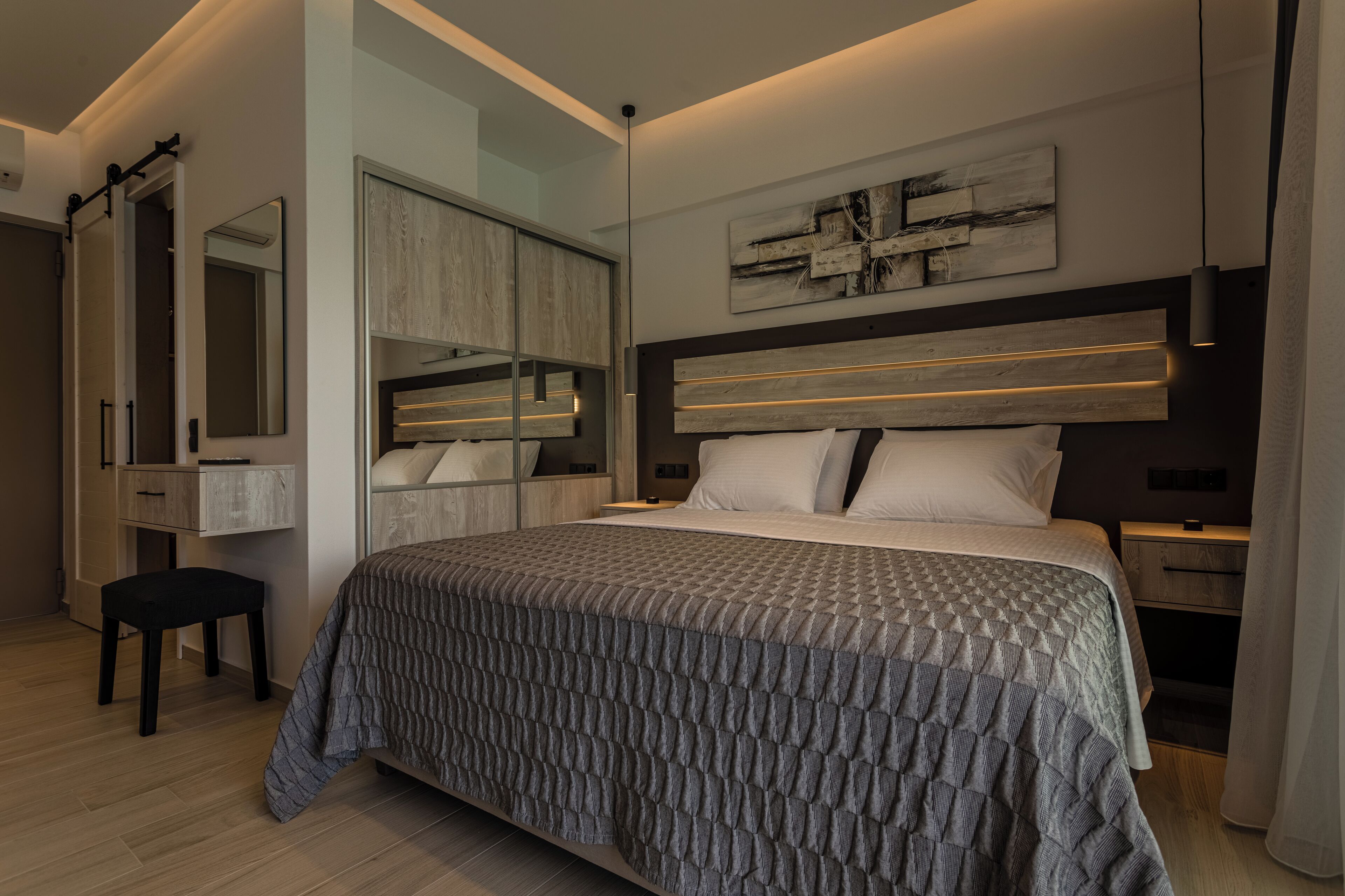 Een moderne slaapkamer met een groot bed, een inbouwkast, een nachtkastje en een kunstwerk aan de muur.
