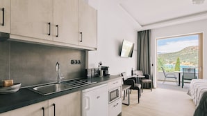 Una cocina moderna con fregadero, estufa y armarios, un comedor con mesa y sillas, y un balcón con vistas al paisaje.