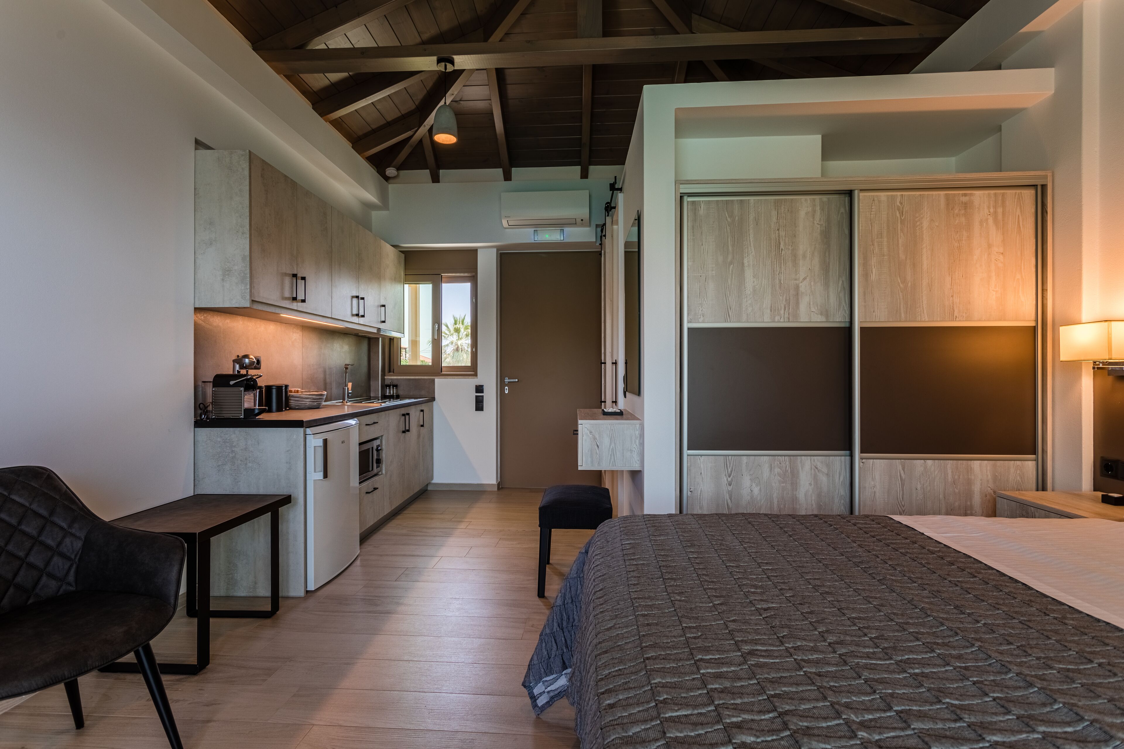 Une chambre d’hôtel moderne équipée d’une kitchenette, d’un lit et d’un coin salon.