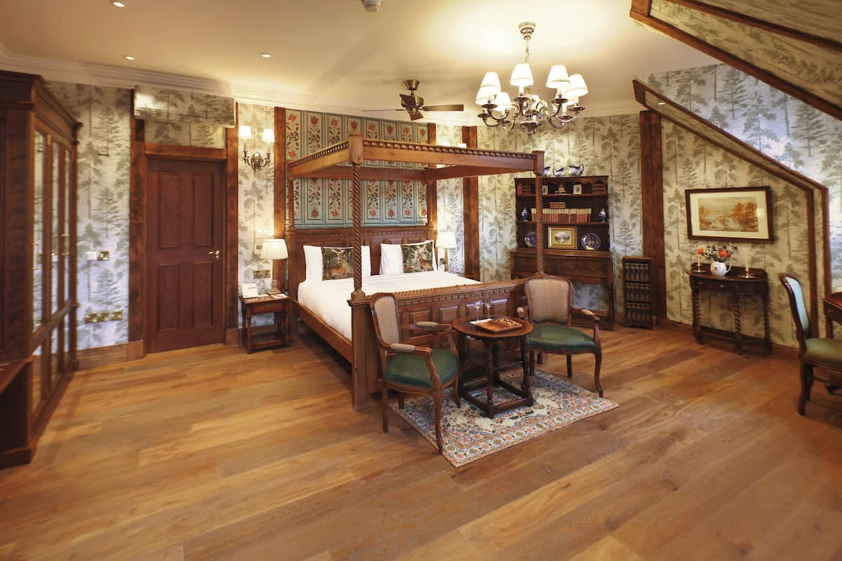 A spacious bedroom with a four-poster bed, a wooden ceiling fan, and a chandelier.