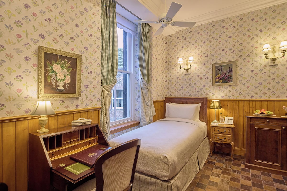 A neatly arranged bedroom with a bed, a desk with a chair, a nightstand, and a dresser.