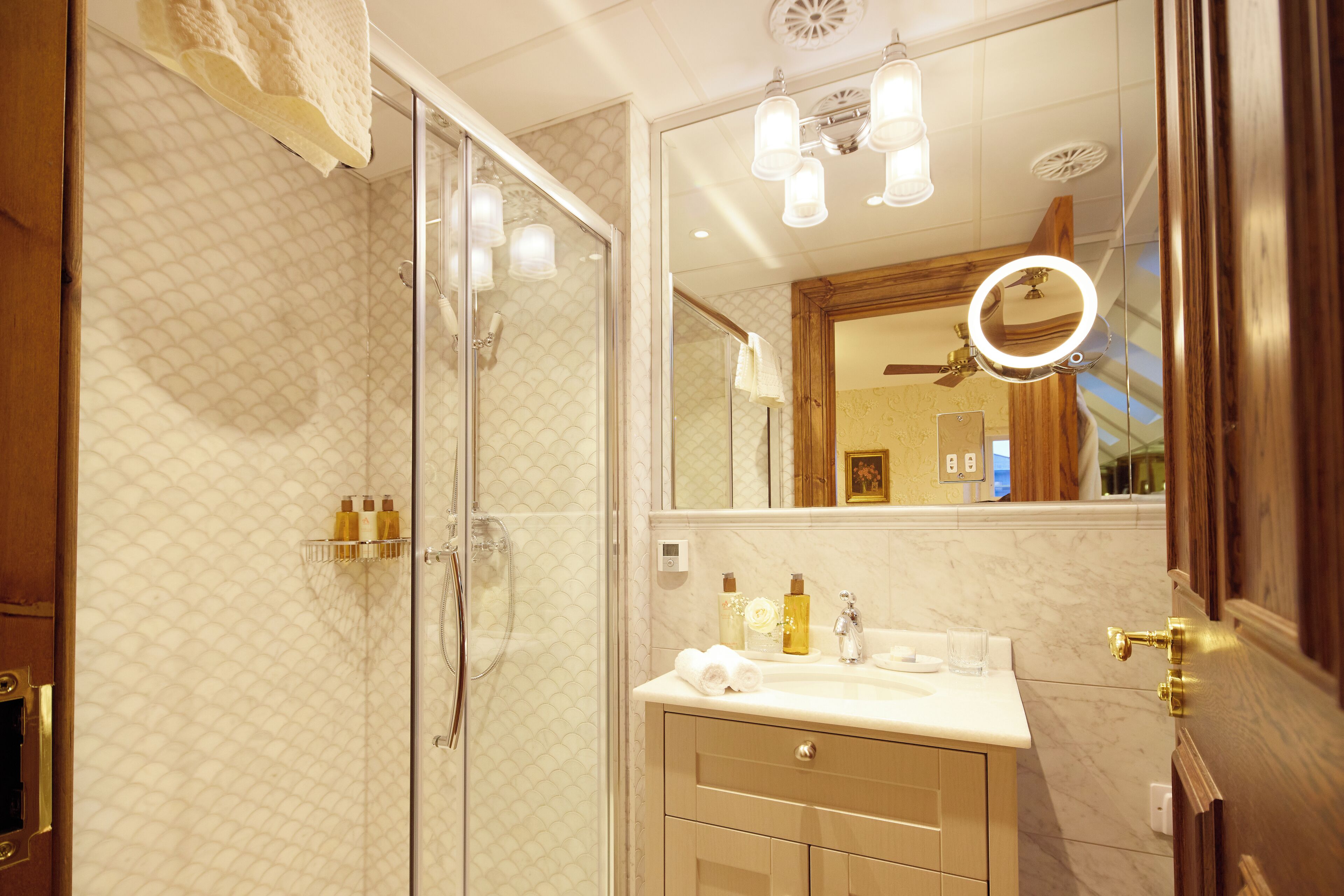 Une salle de bain avec une douche à parois de verre, un meuble-lavabo avec un miroir et un luminaire au plafond.