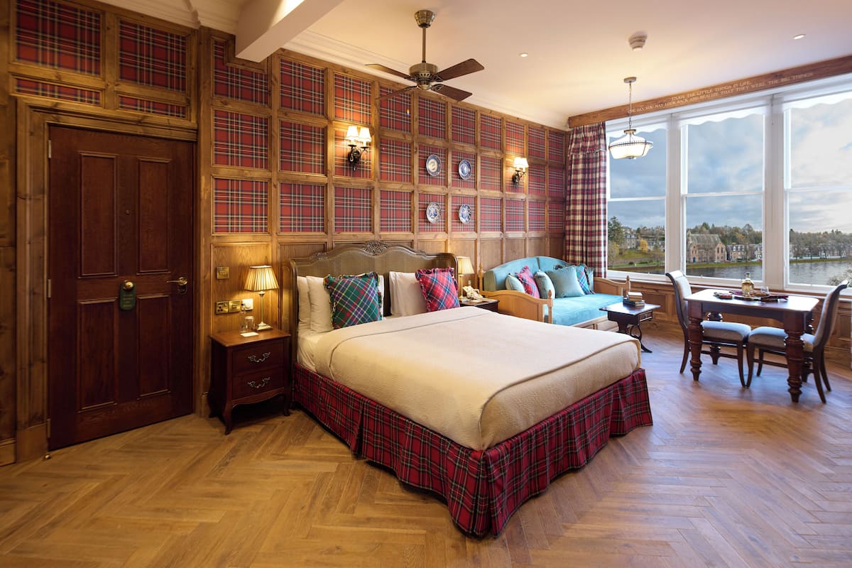 A spacious bedroom with a large bed, a desk, and a view of a lake.