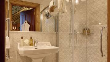 A modern bathroom with a glass-enclosed shower, a pedestal sink, and a mirror with a towel hanging.