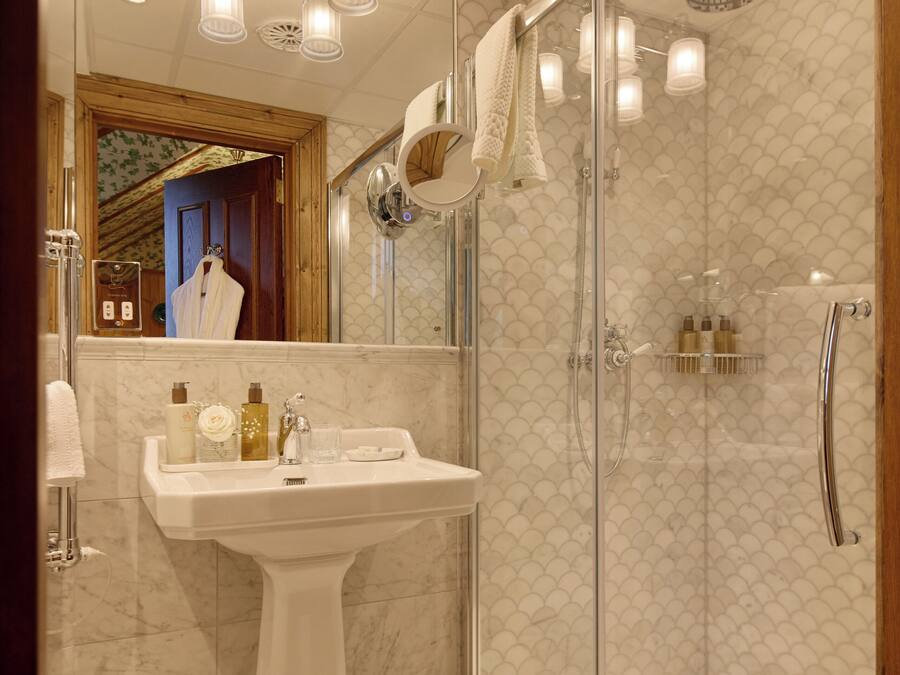 A modern bathroom with a glass-enclosed shower, a pedestal sink, and a mirror with a towel hanging.