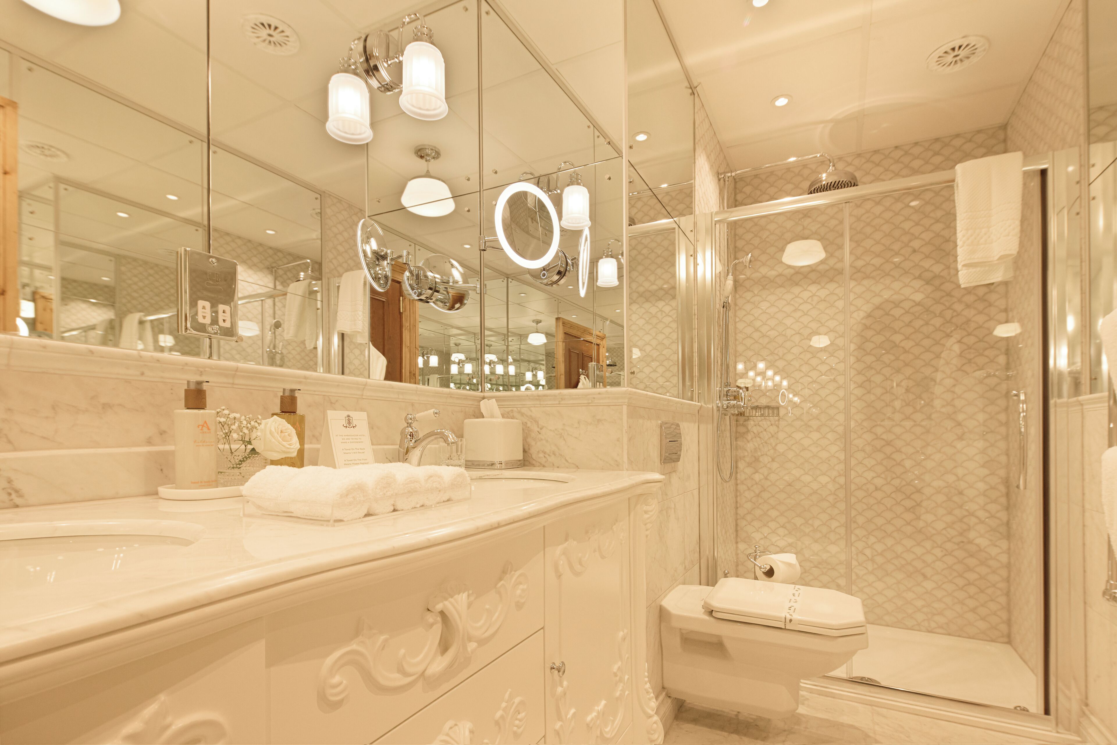 Une salle de bain avec un meuble-lavabo en marbre, un grand miroir, une douche en verre et des toilettes.