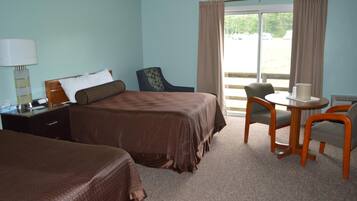 Une chambre d’hôtel avec deux lits, un bureau et une chaise.