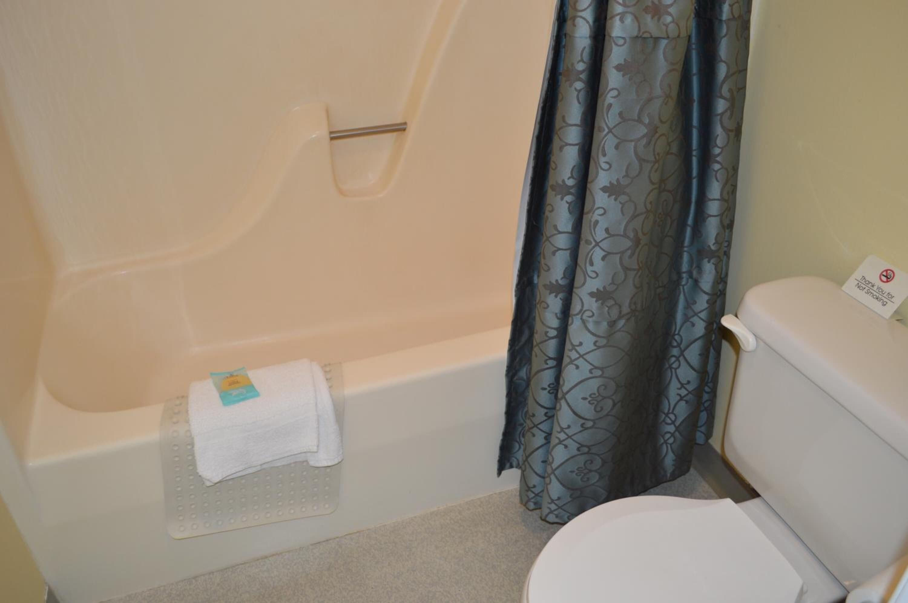 Un baño con bañera, inodoro y cortina de ducha.