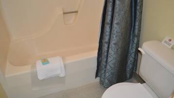 Un baño con bañera, inodoro y cortina de ducha.