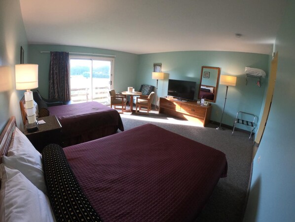 A hotel room with two beds, a TV, a desk, a chair, a small table, and a window with curtains. - Copper Lantern Motor Lodge (West Brookfield)