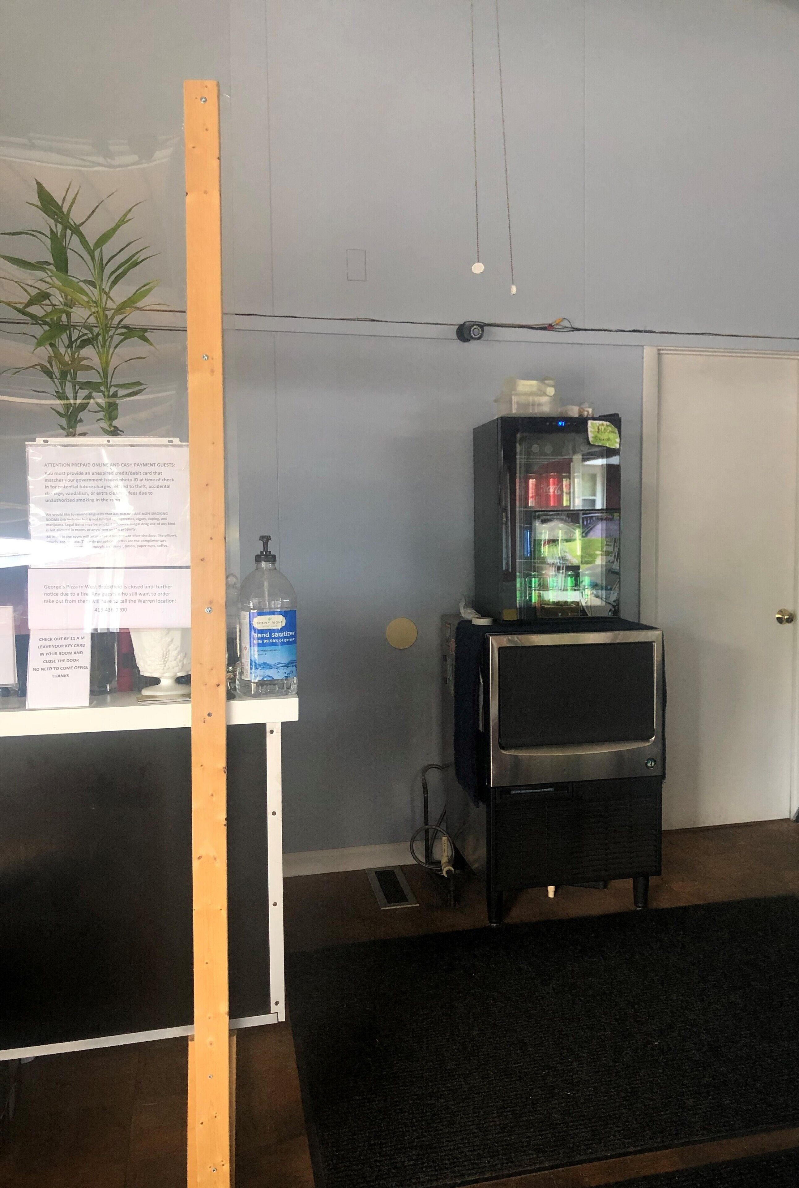 A room with a wooden partition, a vending machine, a bottle of hand sanitizer, and a door.