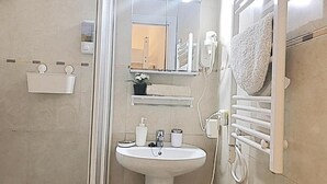 Een badkamer met een wastafel, spiegel, handdoekhouder en douche.