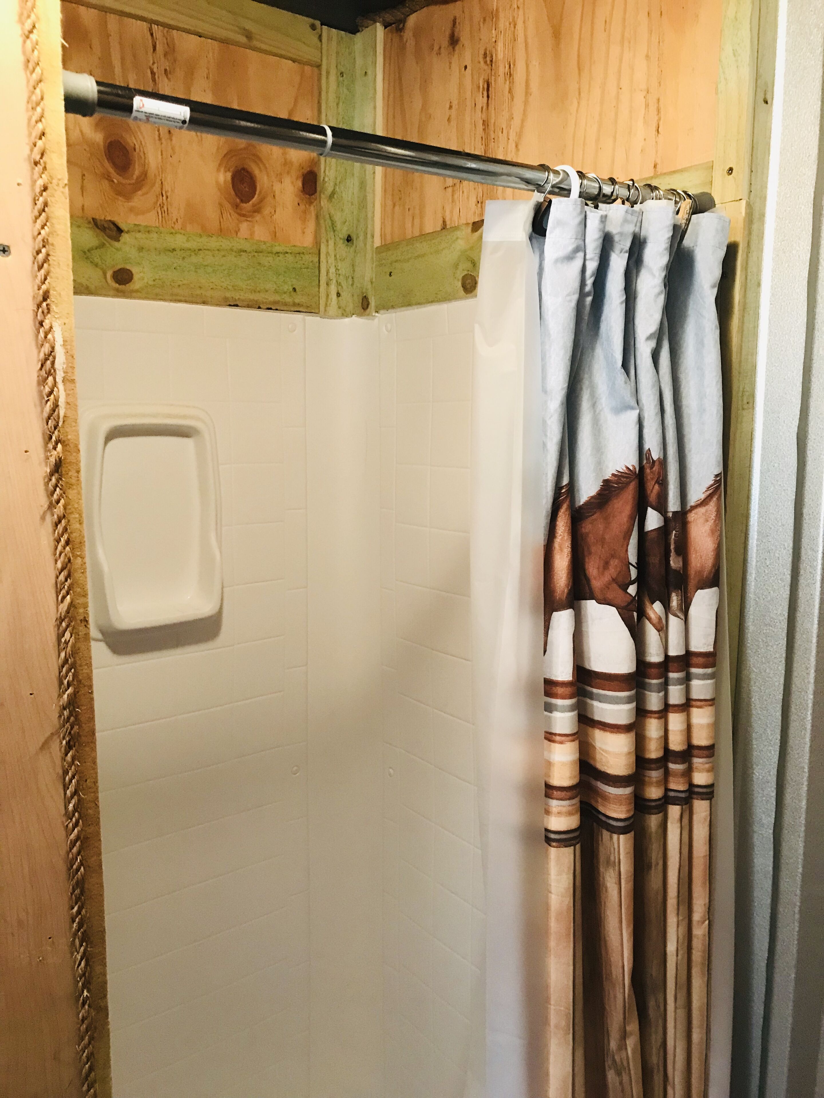 Un espace douche doté d’une porte en bois et d’un mur recouvert de carreaux blancs.