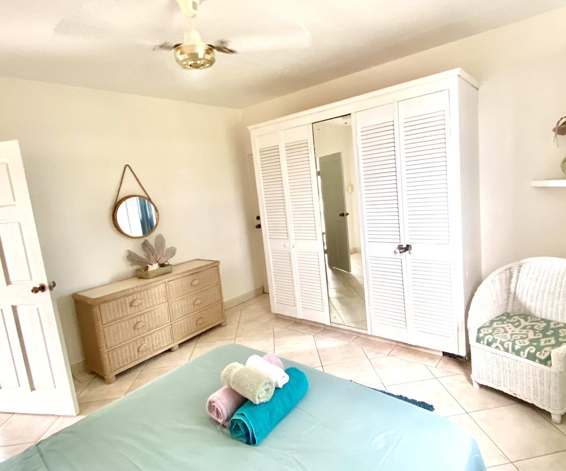 Un dormitorio con cama, cómoda, armario, espejo y silla.