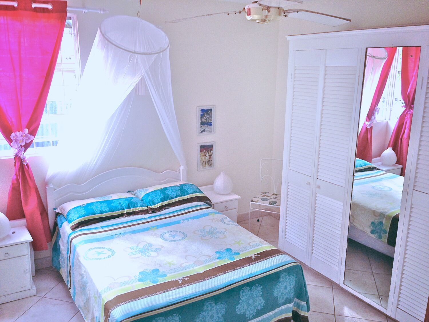 A bedroom with a bed, bedside table, nightstand, and a wardrobe with a mirror.