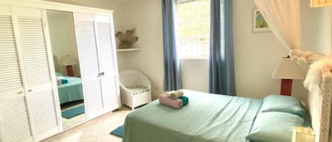 A bedroom with a bed, a wardrobe, a chair, and a window with curtains.