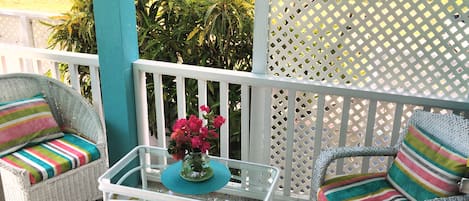 A balcony with wicker chairs, a glass table, and a decorative vase.